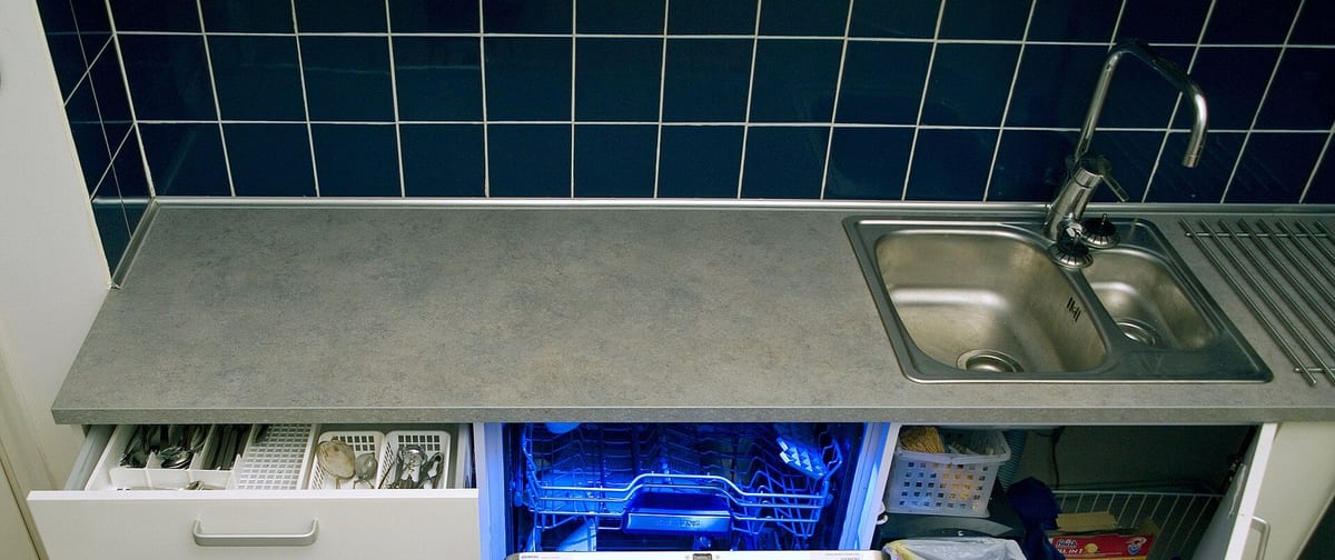 Köksbänk med en öppen, upplyst diskmaskin under bänkskivan