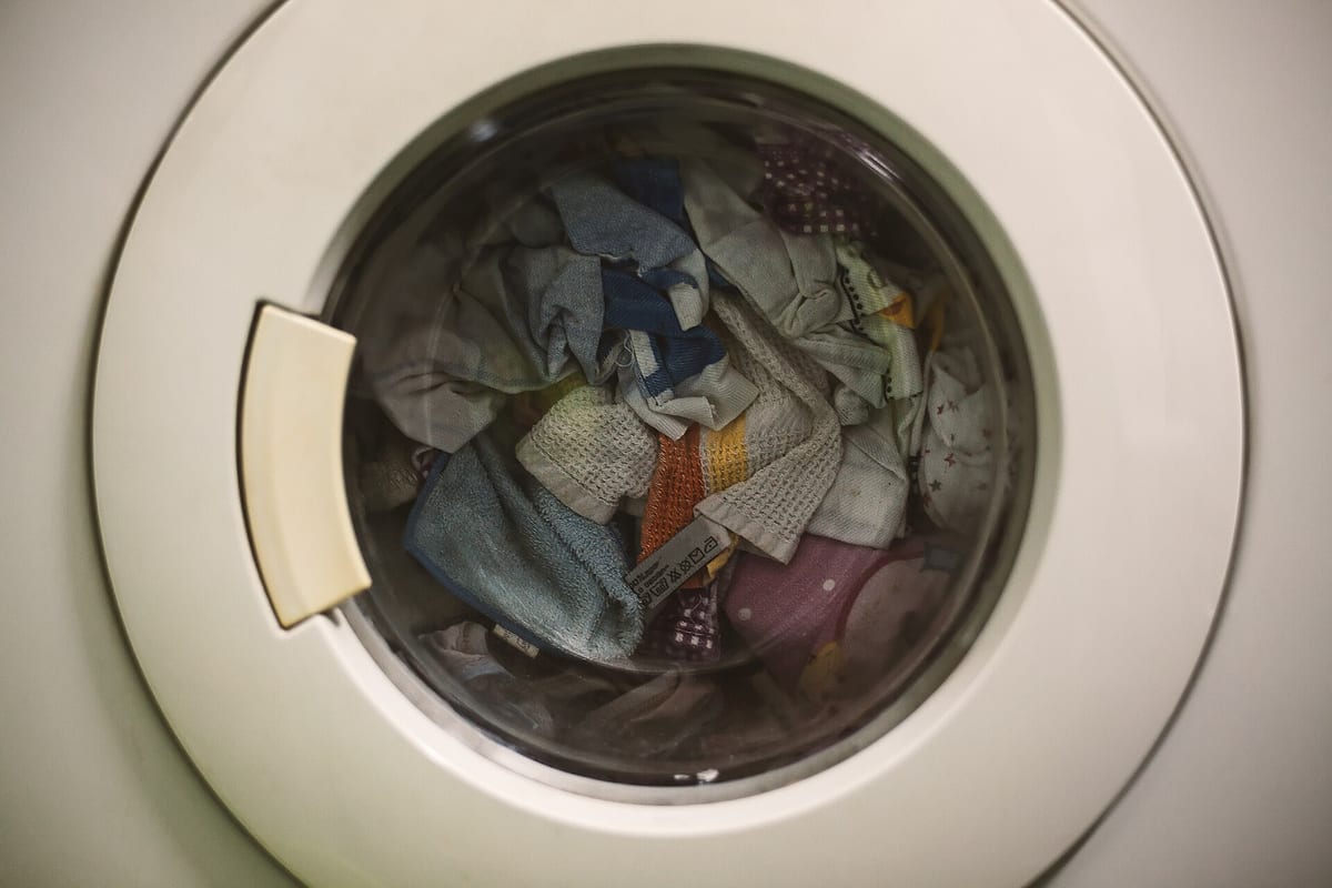 Närbild på luckan till en tvättmaskin med tvätt synlig genom glaset
